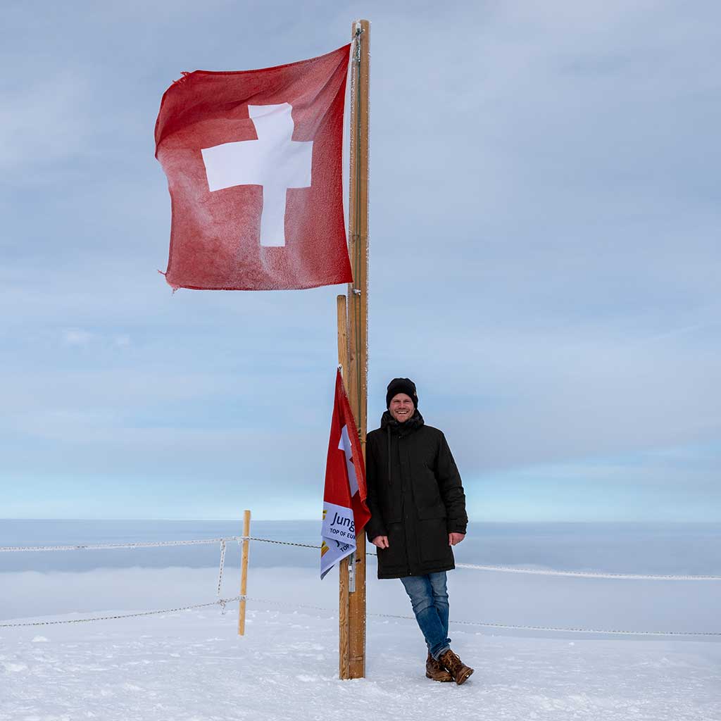 Julian Witting lehnt sich am Top of Europe an den Flaggenmast der Schweizer Flagge