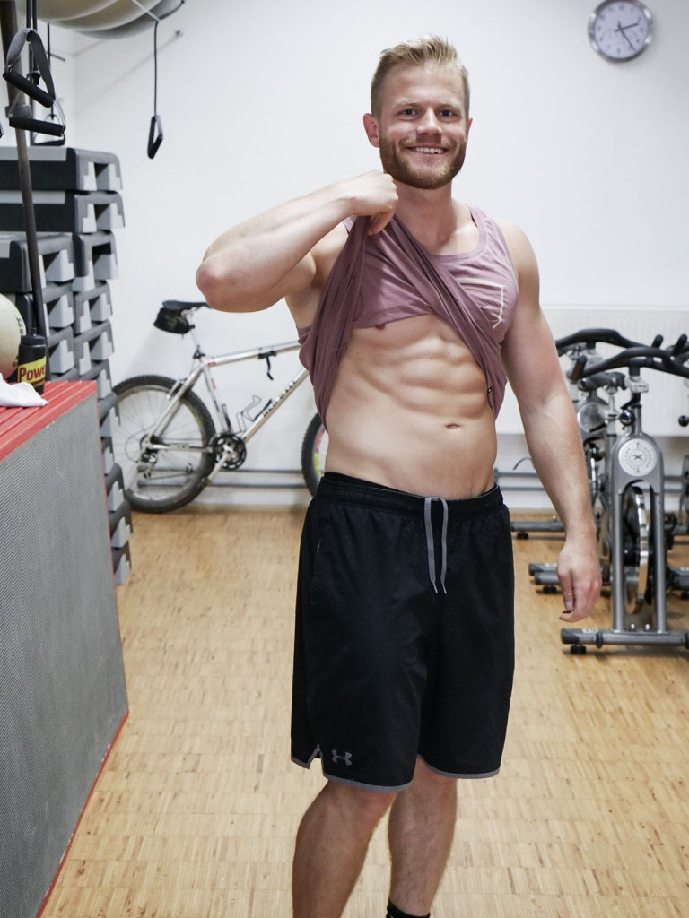 Julian Witting im Fitnessstudio nach dem Workout präsentiert Bauchmuskeln