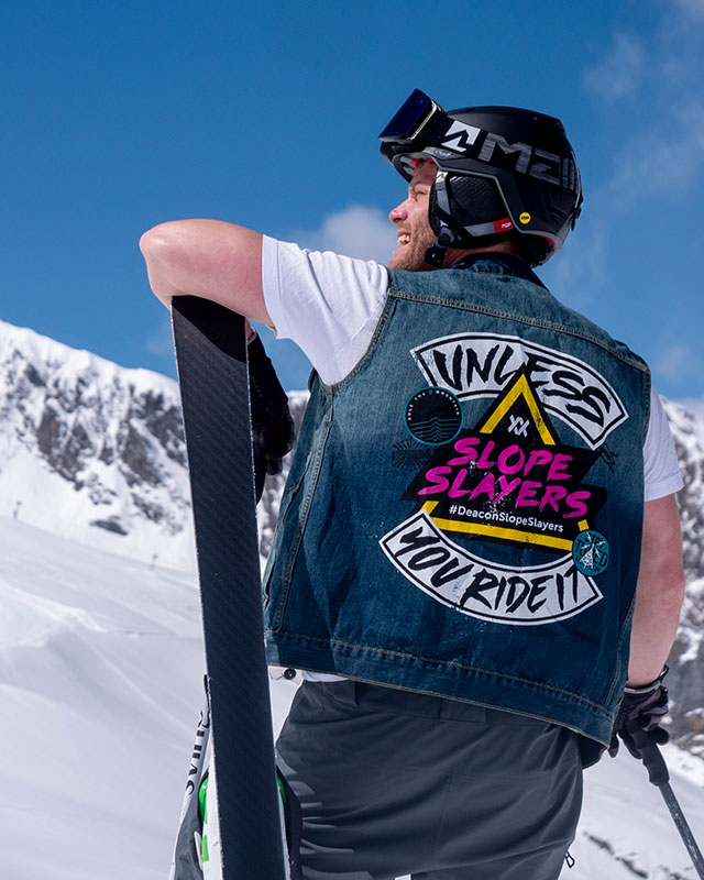 Skifahrer mit Jeansjacke lässig auf den Ski gelehnt und zur Seite blickend