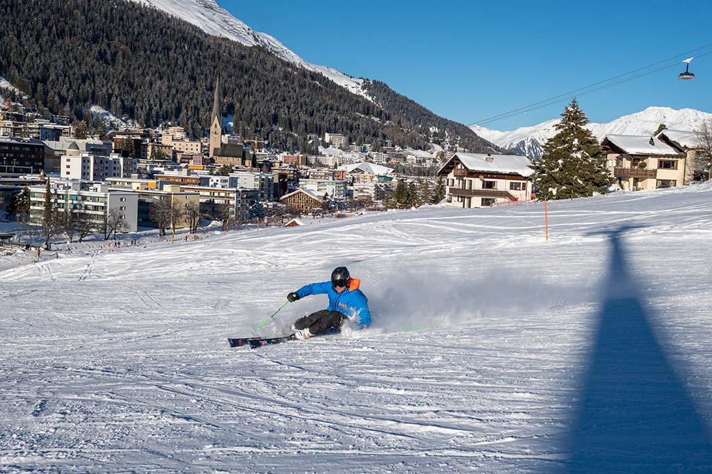 Skifahrer auf Piste vor Stadt in den Bergen
